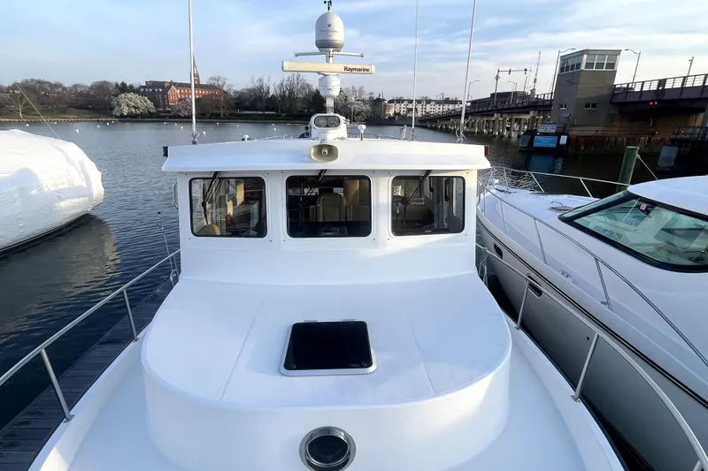 Slide: The Image of 2008 Nordic Tug 42 docked, showcasing its spacious deck and cabin in a serene marina setting. - 55