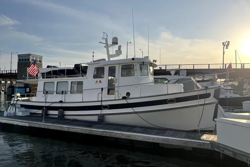 Slide: The Image of 2008 Nordic Tug 42 docked at marina during sunset, displaying American flag. - 6