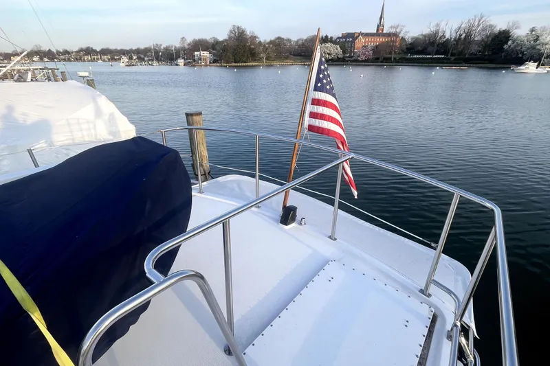 Slide: The Image of Nordic Tug 42 (2008) with American flag, docked by a serene waterfront. - 62