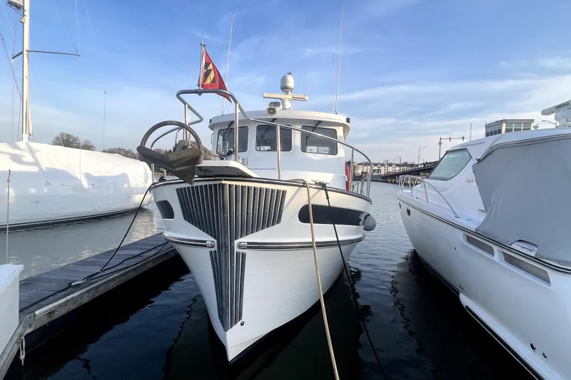 Slide: The Image of 2008 Nordic Tug 42 docked at marina, front view with clear sky background. - 9