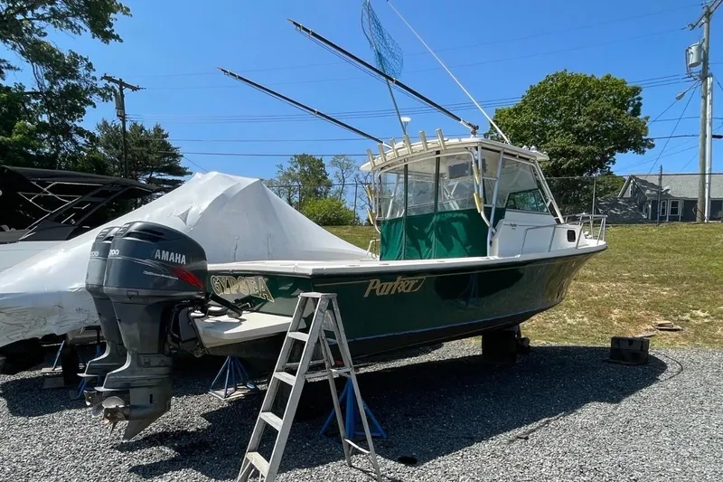 The Image of 2001 Parker 2510 Deep Vee Walkaround boat with Yamaha outboard motor on gravel. - 0