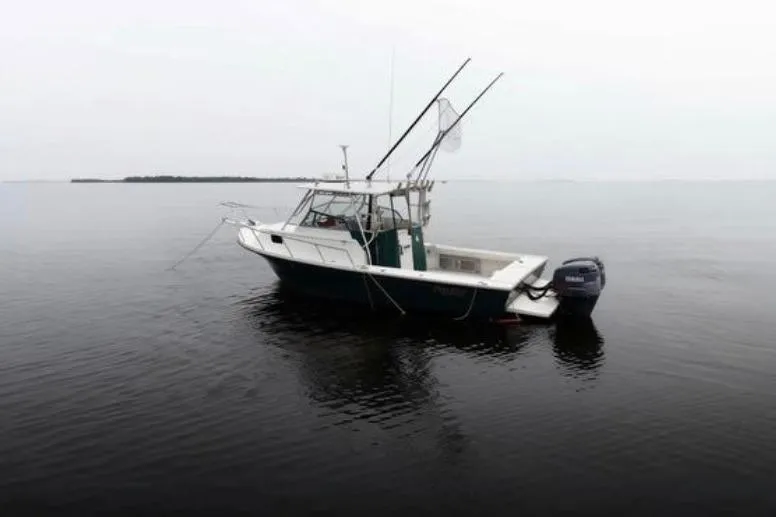 Slide: The Image of 2001 Parker 2510 Deep Vee Walkaround boat on calm water. - 2