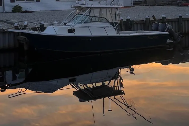 Slide: The Image of 2001 Parker 2510 Deep Vee Walkaround boat docked at sunset, reflecting on calm water. - 6