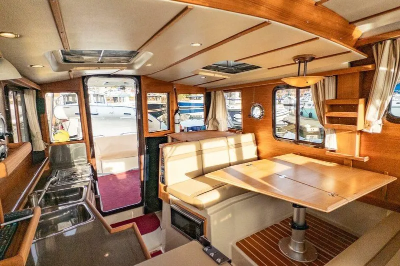 Slide: The Image of 2019 Ranger Tugs R-31-S interior with dining area, kitchenette, and large windows. - 18