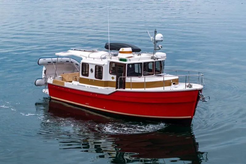 Slide: The Image of 2019 Ranger Tugs R-31-S boat cruising on calm water, featuring a vibrant red hull. - 2