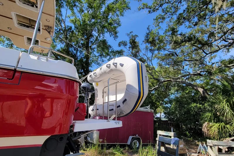 Slide: The Image of 2019 Ranger Tugs R-31-S with inflatable boat, parked outdoors under trees. - 5