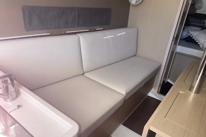 Slide: The Image of Interior of 2020 Beneteau Oceanis 30.1 yacht with white seating and wooden accents. - 5