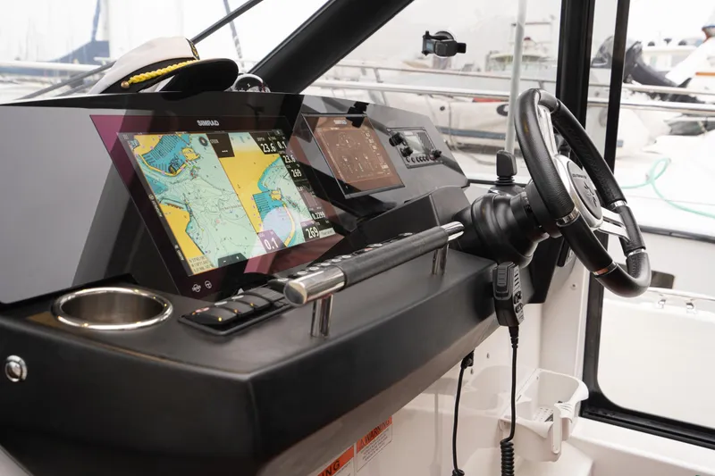 Slide: The Image of 2014 Jeanneau NC 14 helm with navigation screens and steering wheel. - 24