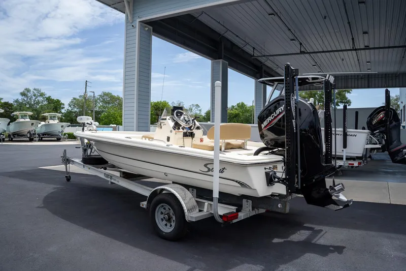 Slide: The Image of 2019 Scout 177 Sportfish Flats boat on trailer under shelter, featuring Mercury outboard motor. - 2