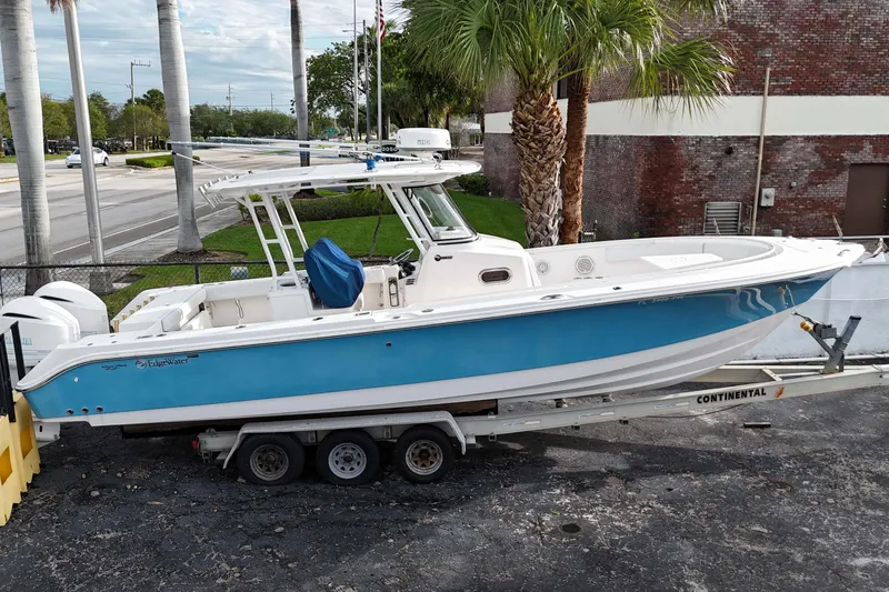 The Image of 2015 Edgewater 320CC boat on trailer, blue and white design, parked outdoors. - 0