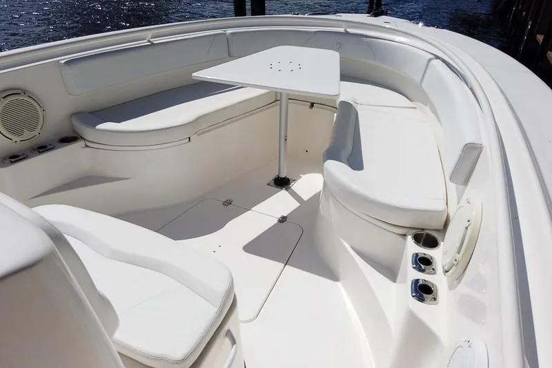 Slide: The Image of 2015 Edgewater 320CC boat interior with white seating and table, docked by water. - 13