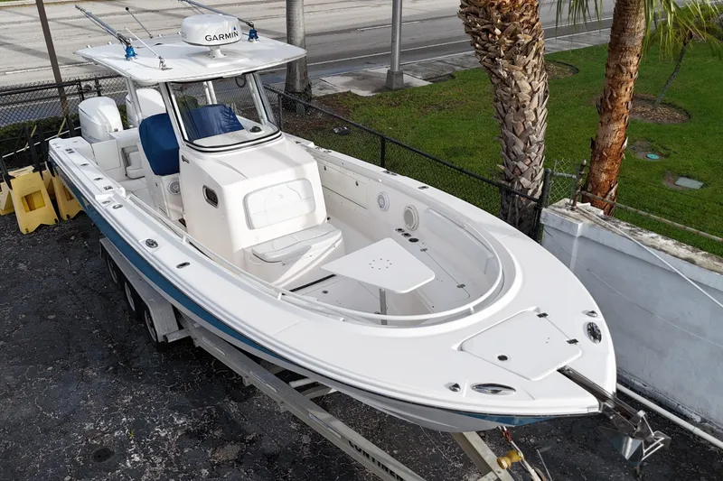 Slide: The Image of 2015 Edgewater 320CC boat on trailer, featuring Garmin equipment, parked near palm trees. - 3
