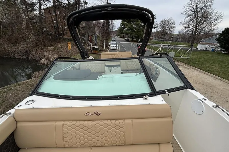 Slide: The Image of 2024 Sea Ray SDX 250 boat with beige seating and black windshield, docked near a road. - 30