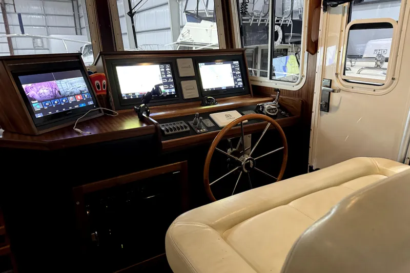 Slide: The Image of 2007 American Tug 34 helm with navigation screens and steering wheel in a cozy cabin. - 14