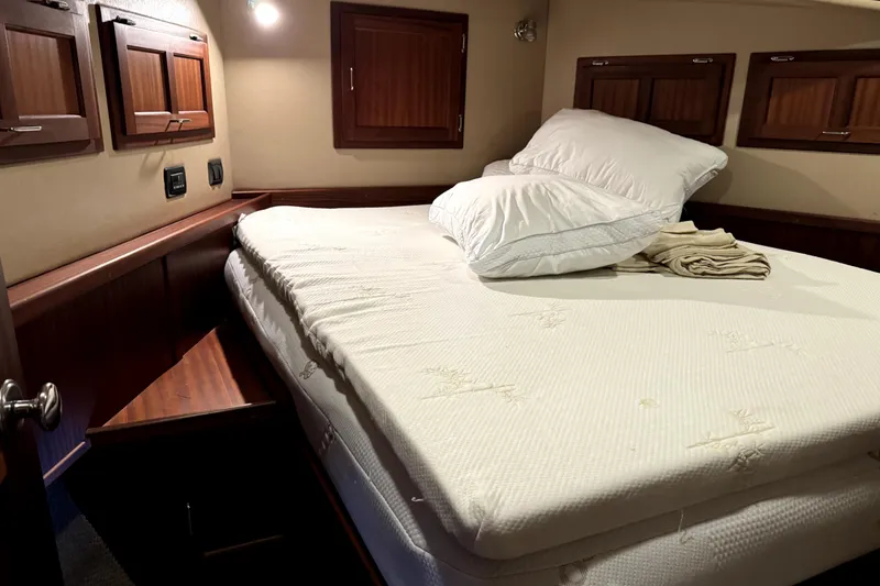 Slide: The Image of Cozy cabin bedroom in a 2007 American Tug 34, featuring a neatly made bed. - 28