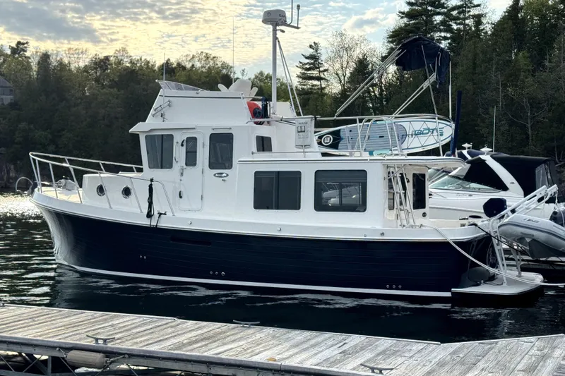Slide: The Image of 2007 American Tug 34 docked at a marina, surrounded by trees and boats. - 3