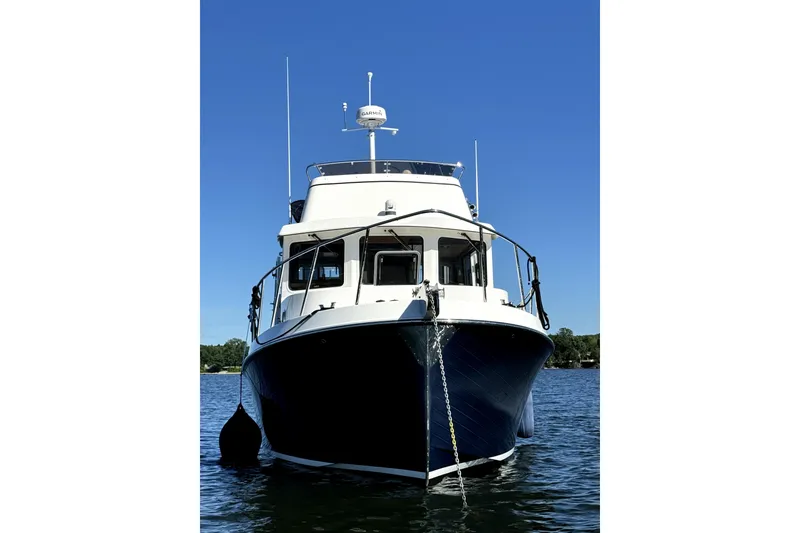 Slide: The Image of 2007 American Tug 34 boat on water, front view under clear blue sky. - 4