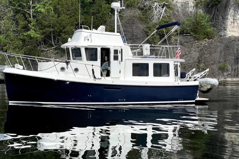 Slide: The Image of 2007 American Tug 34 boat on calm water near rocky shoreline. - 7