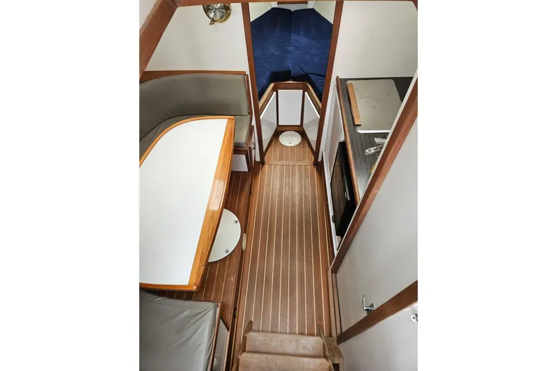 Slide: The Image of Interior of a 1976 Harris boat featuring wood flooring, dining area, and compact kitchen. - 3