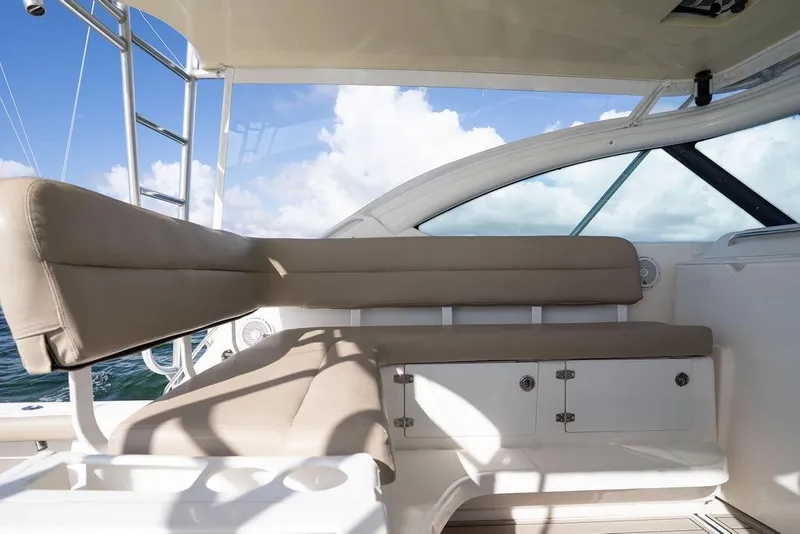 Slide: The Image of 2005 Tiara Yachts 4200 Open interior with beige seating and storage, under a clear sky. - 29