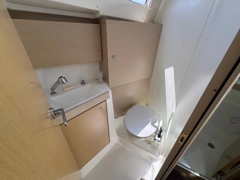 Slide: The Image of 2021 Beneteau Oceanis 35.1 bathroom with sink, toilet, and wooden cabinetry. - 14