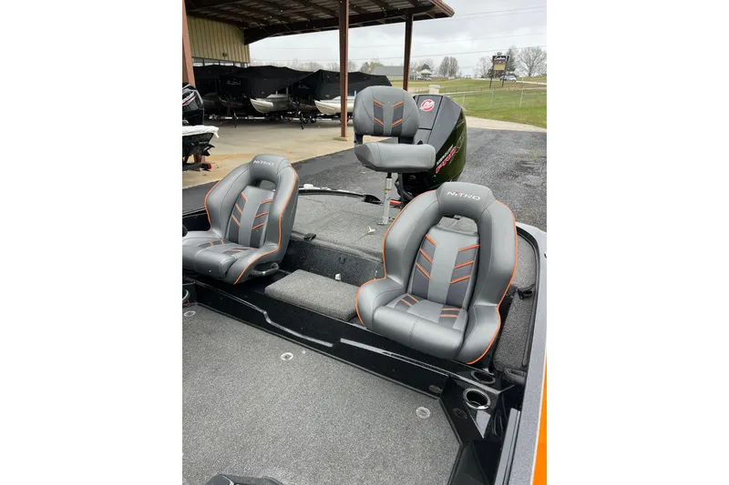 Slide: The Image of 2019 Nitro Z18 boat interior with gray and orange seats, parked under a shelter. - 7