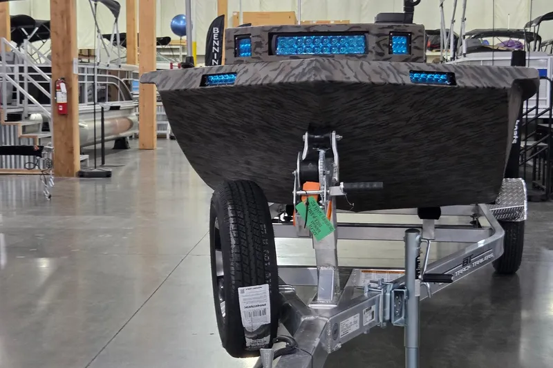 Slide: The Image of 2026 Xpress Bayou 180 boat on trailer in showroom, featuring blue LED lights. - 1