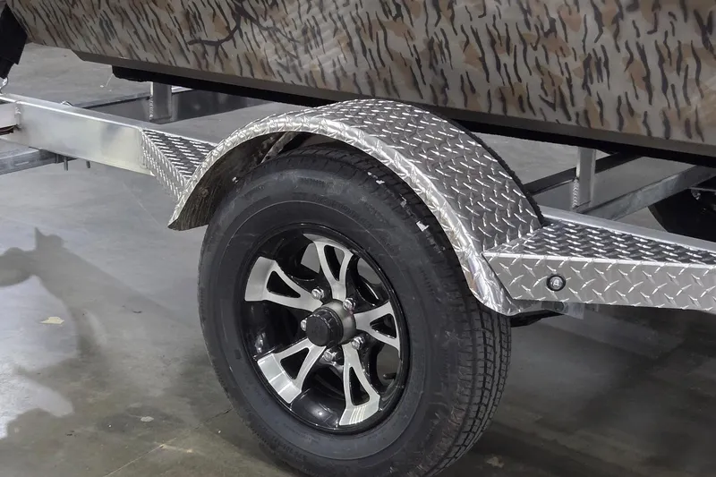 Slide: The Image of Trailer wheel and fender of 2026 Xpress Bayou 180 boat, featuring diamond plate design. - 2