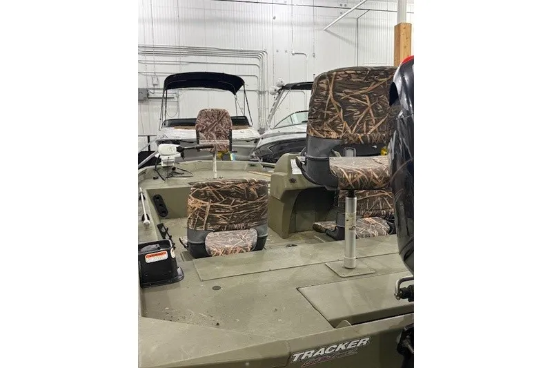 Slide: The Image of 2017 Tracker Grizzly 1754 MVX SC boat with camo seats in a showroom. - 2