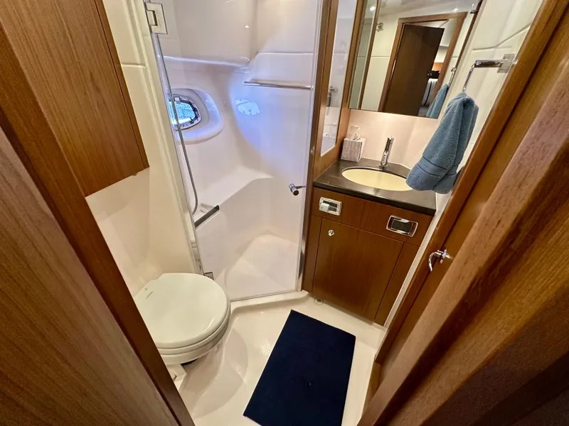 Slide: The Image of 2018 Tiara Yachts 4300 Open bathroom with shower, sink, and wooden cabinetry. - 33