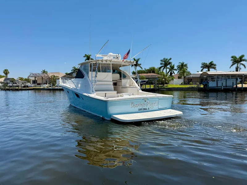 Slide: The Image of 2018 Tiara Yachts 4300 Open cruising on a sunny day, surrounded by palm trees. - 5