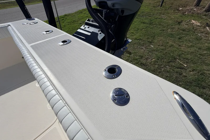 Slide: The Image of Canyon Bay 24H 2010 boat deck with rod holders and motor, parked on grass. - 16