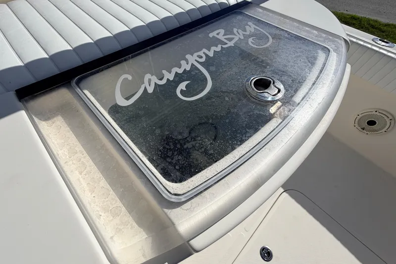 Slide: The Image of Canyon Bay 24H boat deck with logo, featuring a storage compartment, 2010 model. - 23
