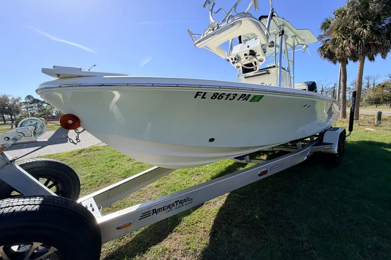 Slide: The Image of 2010 Canyon Bay 24H boat on trailer, parked on grass under clear sky. - 4