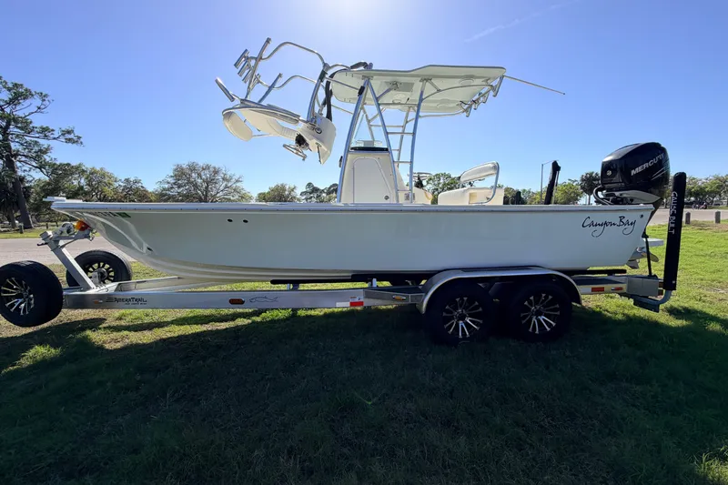 Slide: The Image of 2010 Canyon Bay 24H boat on trailer, parked on grass under clear sky. - 5