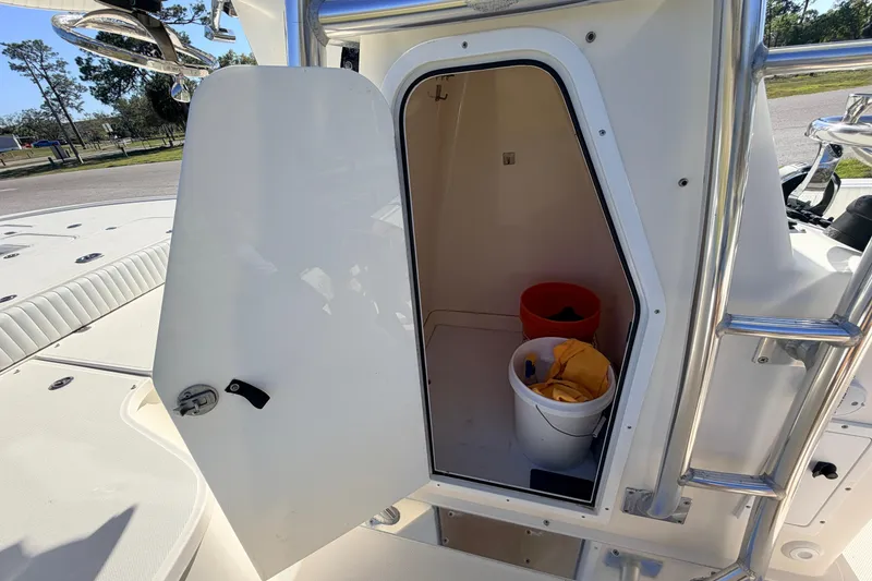 Slide: The Image of 2010 Canyon Bay 24H boat storage compartment with open door, showing buckets and cleaning supplies. - 52