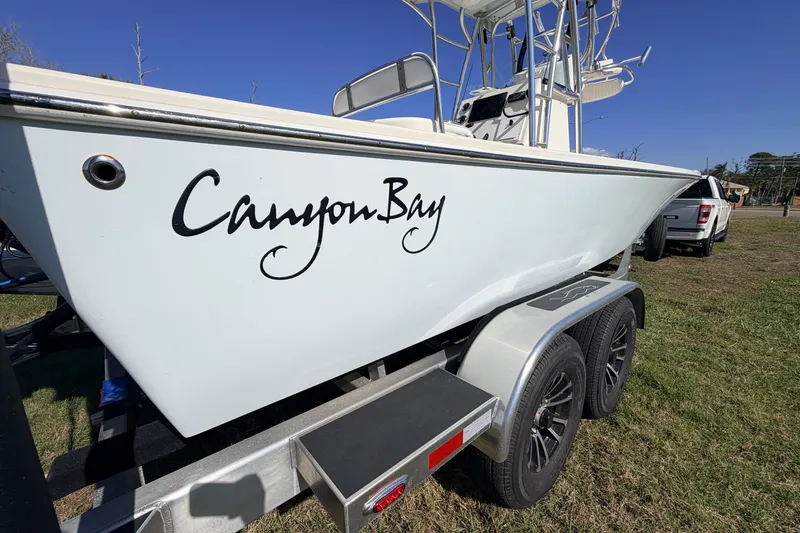 Slide: The Image of 2010 Canyon Bay 24H boat on trailer, parked on grass under clear blue sky. - 94