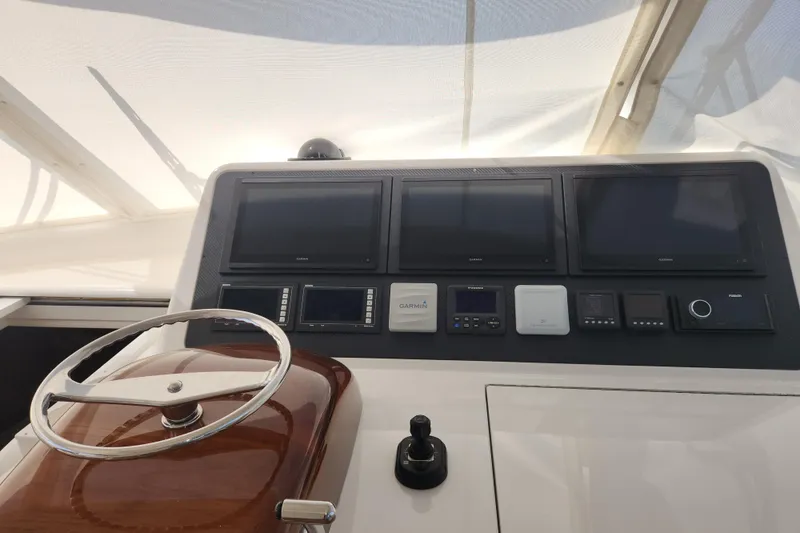 Slide: The Image of Control panel of 2018 Viking 48 Sport Tower with multiple screens and steering wheel. - 15