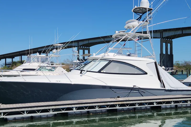 Slide: The Image of 2018 Viking 48 Sport Tower yacht docked near a bridge on a sunny day. - 2