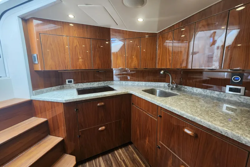 Slide: The Image of Luxurious kitchen interior of 2018 Viking 48 Sport Tower yacht with wood cabinetry and granite countertops. - 52