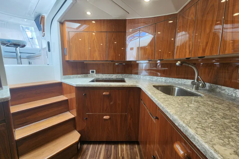 Slide: The Image of Luxurious kitchen interior of 2018 Viking 48 Sport Tower yacht with wood cabinetry and granite countertops. - 58