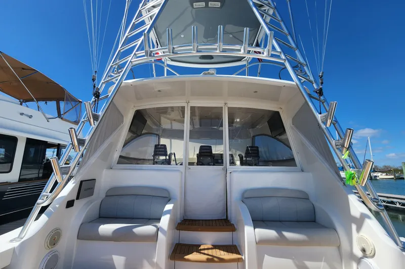Slide: The Image of 2018 Viking 48 Sport Tower yacht with seating, ladder, and clear sky background. - 96