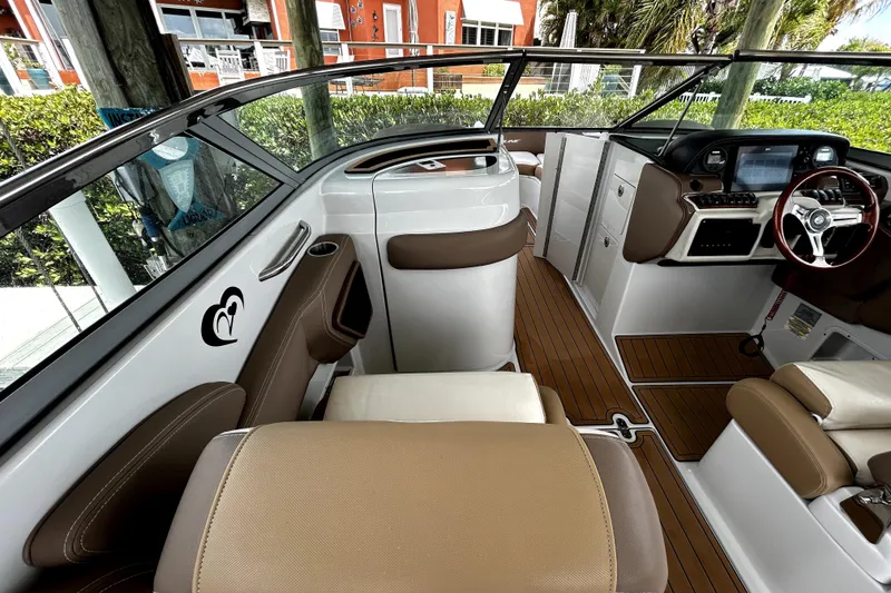 Slide: The Image of 2017 Crownline Eclipse E29 XS boat interior with brown and white seating, modern dashboard, and wood flooring. - 14