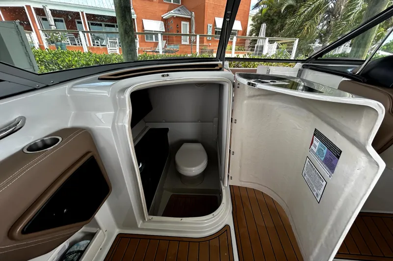 Slide: The Image of 2017 Crownline Eclipse E29 XS boat interior with open bathroom door and visible toilet. - 19