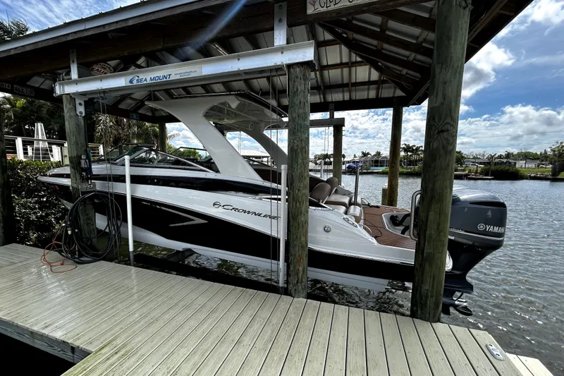 Slide: The Image of 2017 Crownline Eclipse E29 XS boat docked under a covered structure by the water. - 2