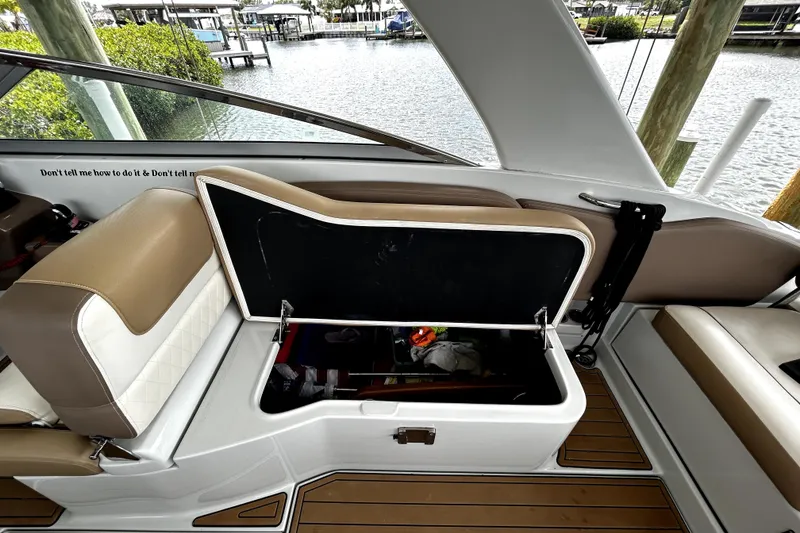 Slide: The Image of 2017 Crownline Eclipse E29 XS boat interior with open storage compartment, tan and white seating. - 44
