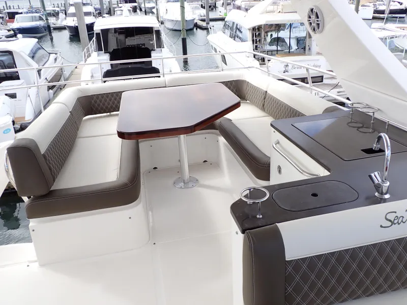 Slide: The Image of 2015 Sea Ray 510 Fly yacht with elegant outdoor seating and dining area at marina. - 24