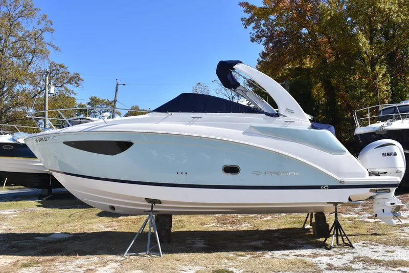 The Image of 2024 Regal 26 XO boat with Yamaha engine, displayed outdoors on stands. - 0