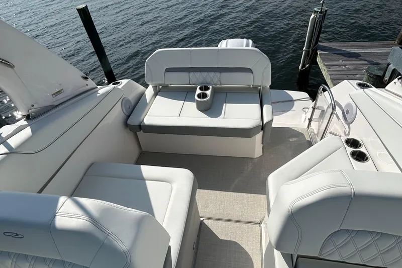 Slide: The Image of 2024 Regal 26 XO boat interior with white seating and cup holders by the water. - 11