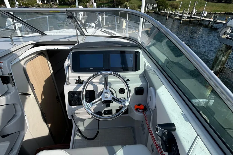 Slide: The Image of 2024 Regal 26 XO boat cockpit with steering wheel and dual screens, dockside view. - 12